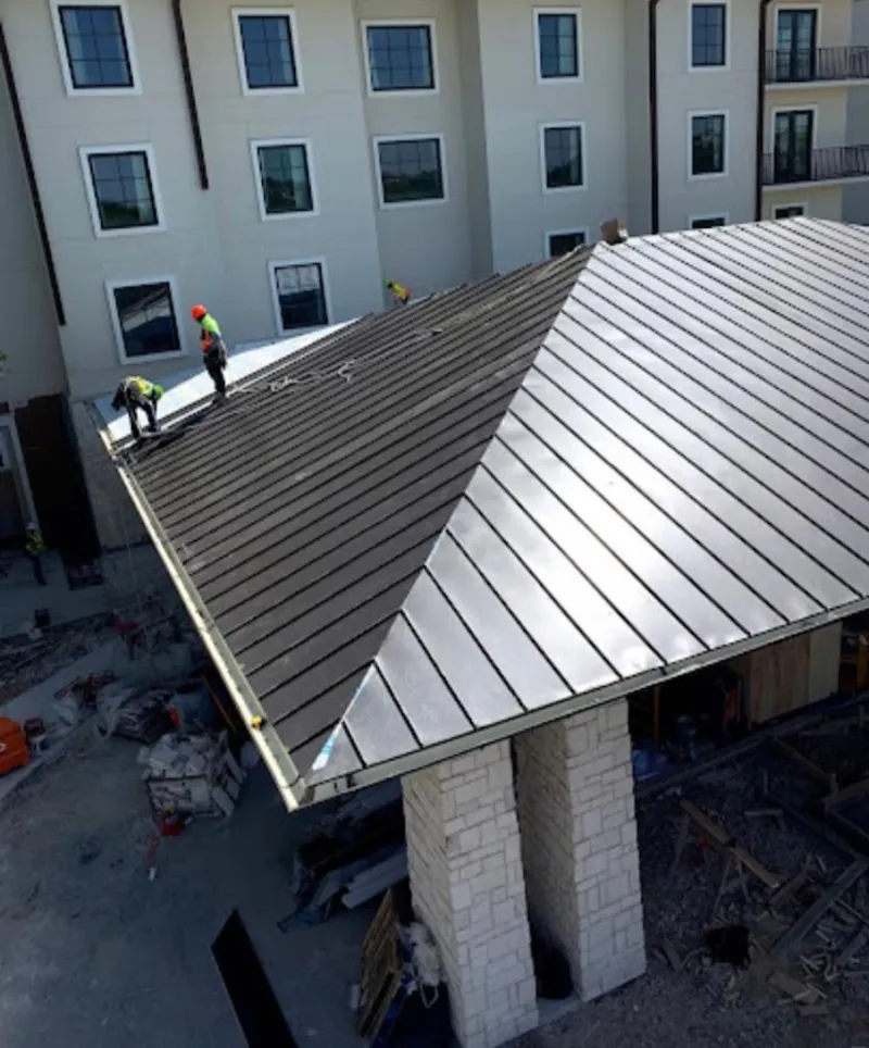 Crew installing standing seam metal roof panels on a commercial project in Doylestown